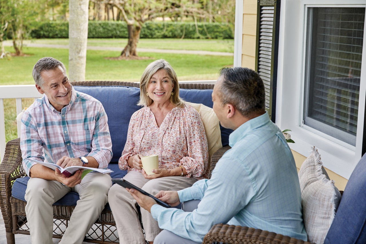 Senior couple sitting on porch with agent reviewing brochure