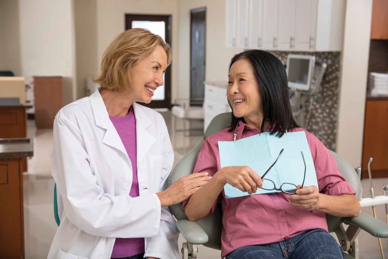 Senior woman sitting in dentist chair getting ready for dental visit with female dentist